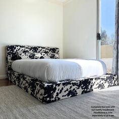 a bed that is in the middle of a room with a cow print headboard