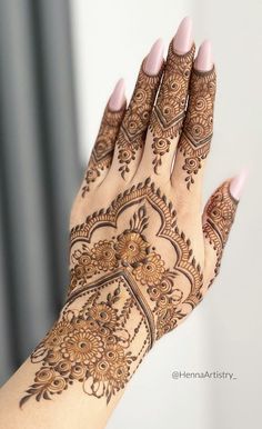 a woman's hand with henna tattoos on her arm and hands, showing the intricate design