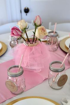 there is a table set with pink and white flowers in mason jars