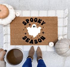 a door mat that says spooky season next to two cups of coffee