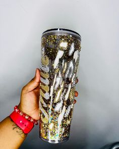 a person holding up a cup filled with lots of different colored beads and chains on it