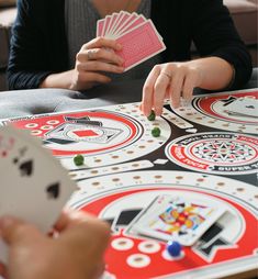 two people playing a card game at a table with cards in front of their hands