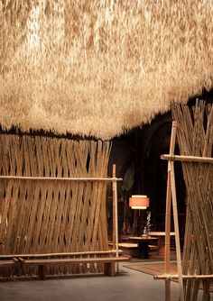 the interior of a hut made out of straw and bamboo sticks with lamps on either side