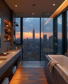 a bathroom with large windows and a view of the city at sunset in the background