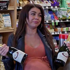 a pregnant woman holding two bottles of wine