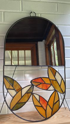 a stained glass mirror sitting on top of a wooden table