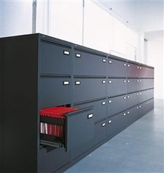 a woman is walking through a large room with many drawers on the wall and file cabinets in front of her