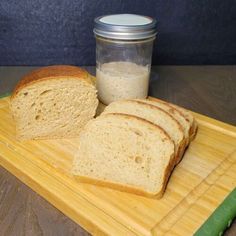 two slices of bread on a cutting board next to a jar of peanut butter