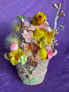 a yellow bird sitting on top of a basket filled with flowers and other things in it