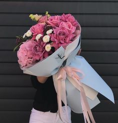 a woman holding a large bouquet of pink and white flowers