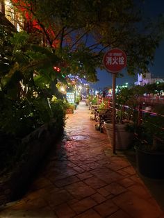 a red and white street sign sitting on the side of a brick road at night