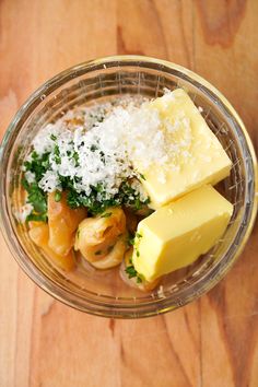 some food is in a glass bowl on a wooden table