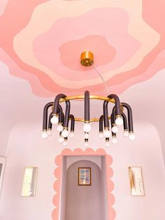 a chandelier hanging from the ceiling in a room with pink and white walls