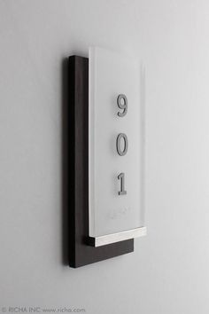 a white and black clock mounted to the side of a wall with numbers on it