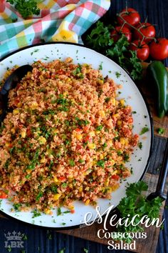 mexican couscous salad on a white plate with tomatoes and parsley in the background