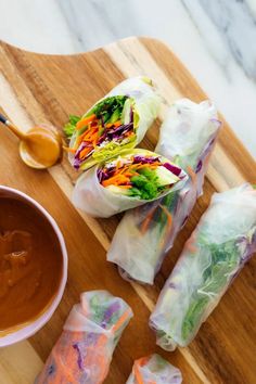 several rolls on a cutting board with dipping sauce