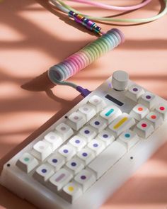 a white keyboard sitting on top of a table next to a colorful corded device