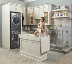 a woman and her dog are sitting on the kitchen island in front of the washer