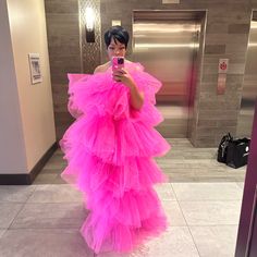 a woman in a pink dress taking a selfie with her cell phone at the elevator