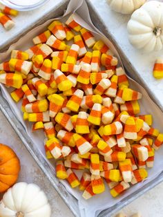 a tray filled with candy corn on top of a table next to other pumpkins