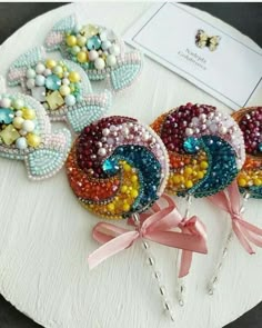 three lollipops are sitting on top of a white plate with pink bows