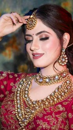 a woman in a red and gold outfit with jewelry on her head, posing for the camera