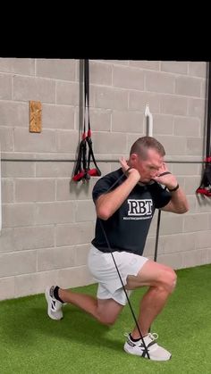 a man squats on the ground while holding his hands behind his head