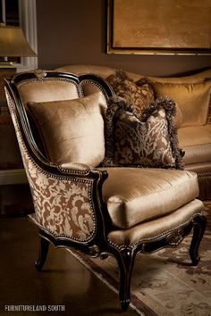 an ornate chair with pillows on it in front of a lamp and painting behind it