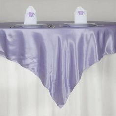 two white plates on top of a table covered in purple cloth with matching napkins