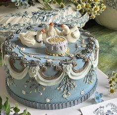 there is a cake decorated with three birds on the top and flowers in the background