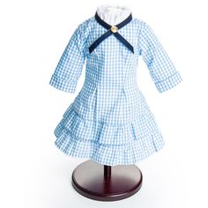 a blue and white checkered dress on a wooden stand with a black ribbon around the collar