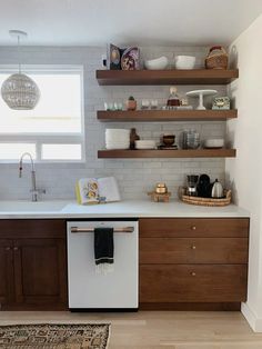 a white dishwasher sitting inside of a kitchen next to wooden cabinets and shelves