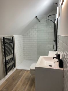 an attic bathroom with white tile and wood flooring