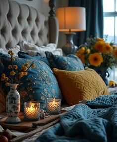 a bed with blue and yellow pillows, candles and vases on the headboard