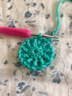 the crochet ball is being worked on by a pink handled crochet hook