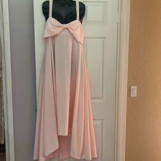 a dress hanging on a door with a pink bow at the top and bottom,