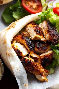 chicken wraps with lettuce, tomatoes and sauce on the side are ready to be eaten