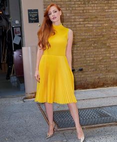 a woman in a yellow dress posing for the camera