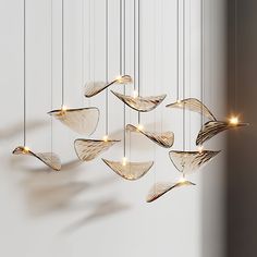 a group of lights hanging from strings in the shape of fish's tails on a white wall