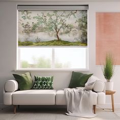 a white couch sitting under a window next to a potted plant and green pillows