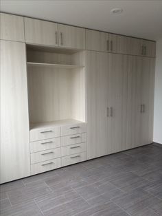 an empty room with white cupboards and grey tile flooring on the ground,