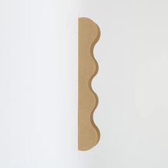 a white wall with a piece of cardboard on top of it and a brown object in the middle