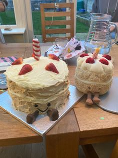 two cakes sitting on top of a wooden table next to each other with strawberries