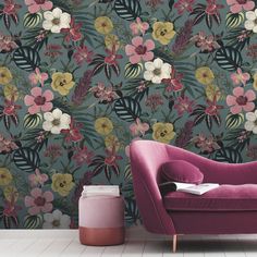 a pink chair sitting in front of a wallpaper with flowers and leaves on it