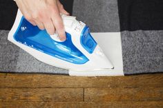 a person ironing fabric with a blue and white steam iron