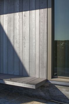 a wooden bench sitting next to a window on the side of a building in front of a door