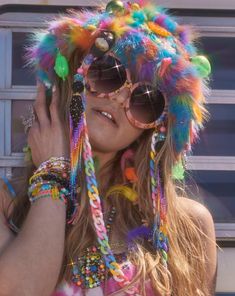 A vibrant festival outfit featuring a colorful furry hat with neon accents, paired with oversized round sunglasses and layered beaded jewelry, evoking a Grateful Dead concert vibe with Dancing Bears and hippie style aesthetics. Pink Rave Accessories, Music Festival Crafts, Neon Rave Outfits, Weird Accessories, Plus Size Rave, Edc Orlando, Sparkle Fashion, Rave Hats, Edm Music Festivals