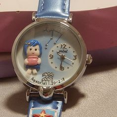 This Mini Brand Handcrafted Watch Is A Unique Timepiece That Features A Zodiac Theme. The Hand Created And Hand Painted Decorations On The Front Of The Watch Features A Character With Blue Hair, They Are Wearing A Blue Dress & Gold Hairclip. They Are Holding A Pink Jar. As With All Of The Zodiac Watches, The Constellation Is Featured With Silver Stars At The Top Of The Face & The Sign Is Shown At The Bottom Of The Face In Crystals Above The Name & Dates Of The Sign. The Watch Has A Round Shape W Artsy Gifts For Friends, Character With Blue Hair, Cute Figurines, Zodiac Watches, Wishlist Ideas, Arabic Numbers, Artsy Gift, Face Features, Toy Watch