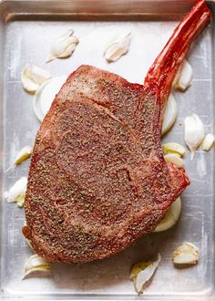 a piece of meat sitting on top of a pan covered in garlic and seasoning