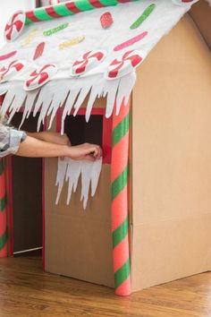 a child playing in a cardboard house made to look like candy canes and marshmallows